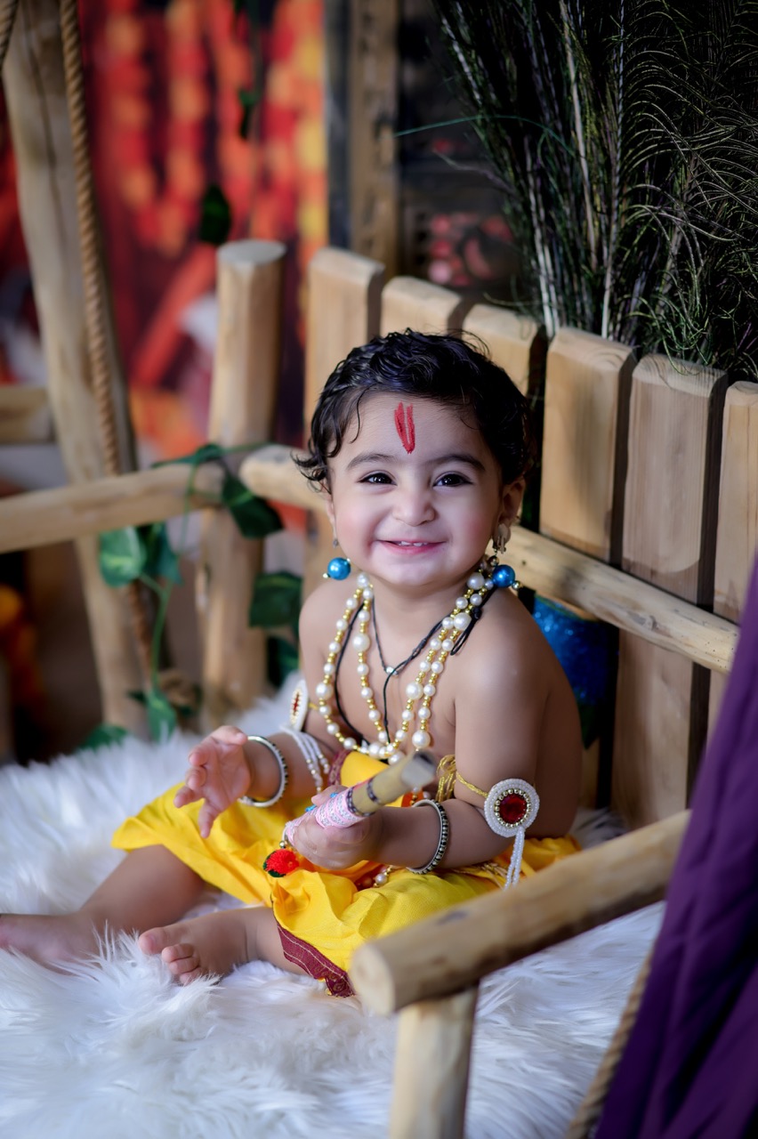 Smiling baby boy dressed as little Krishna on a jhula